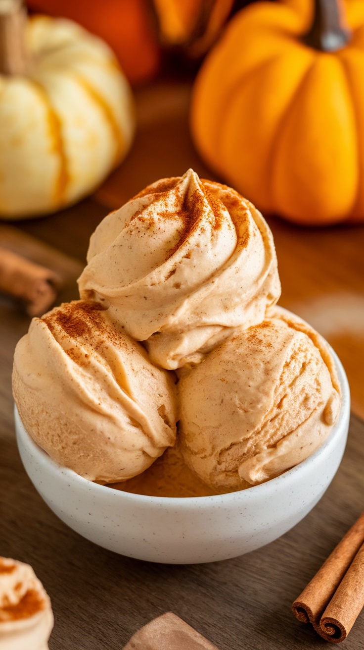A bowl of creamy pumpkin spice nice cream topped with cinnamon, surrounded by pumpkins and cinnamon sticks.